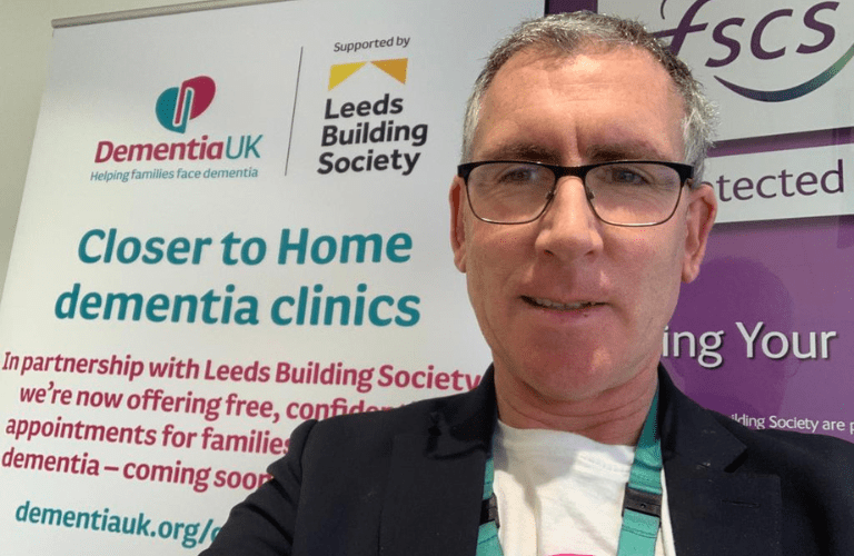 Admiral Nurse JOe Costello in front of a Dementia UK service banner