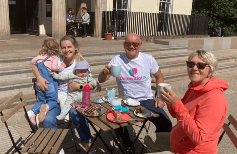 Steve, a volunteer, shares a cup of tea with friends outside.