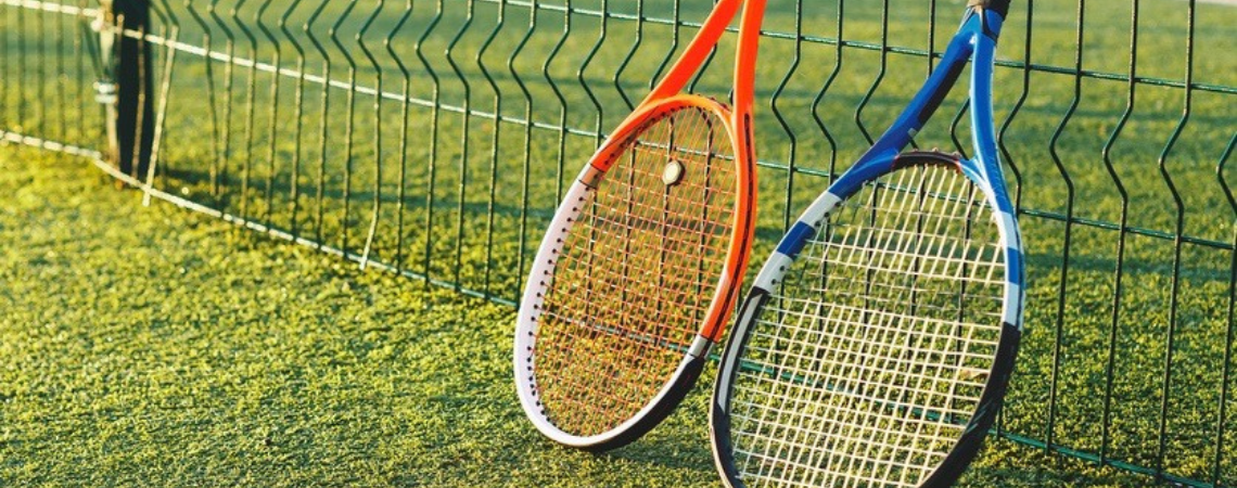 A pair of tennis rackets propped against a tennis net
