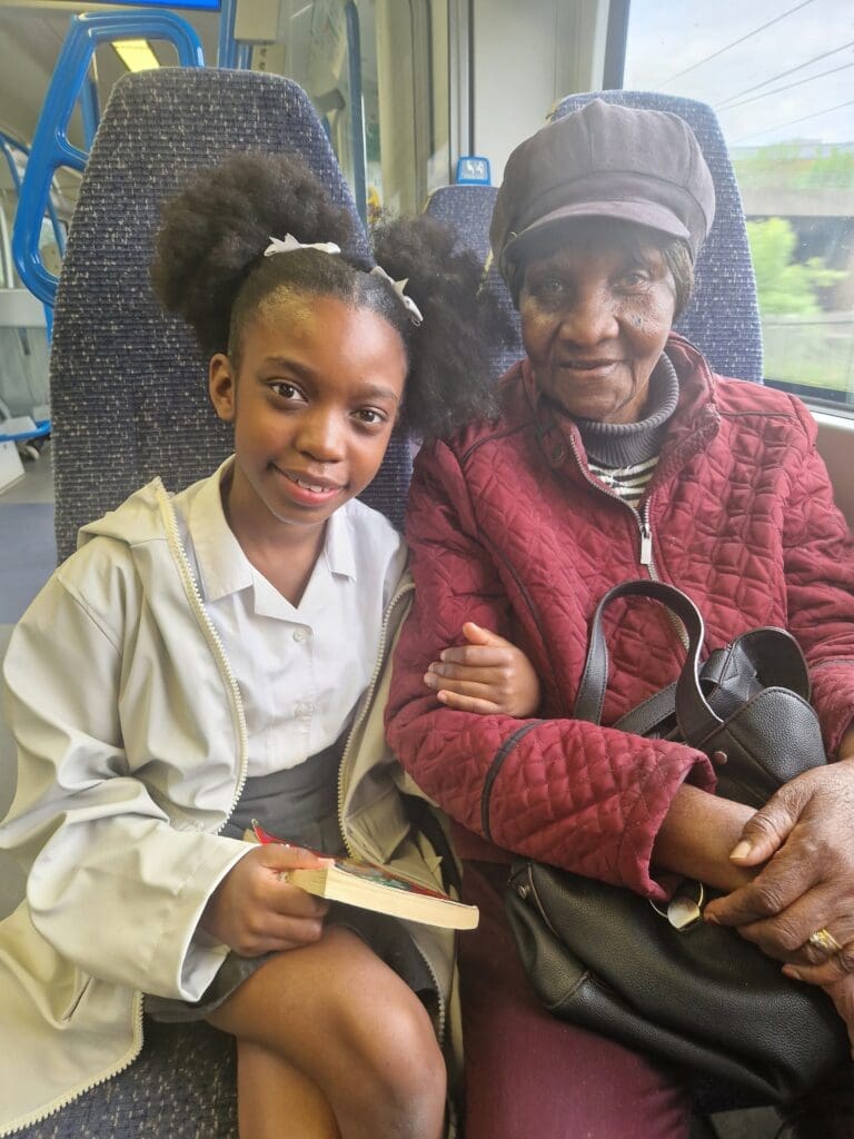 Tiana holds the arm of Vanda on a train