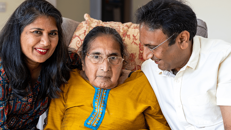 Manjula sits between Nishma and Mahersh on a chair