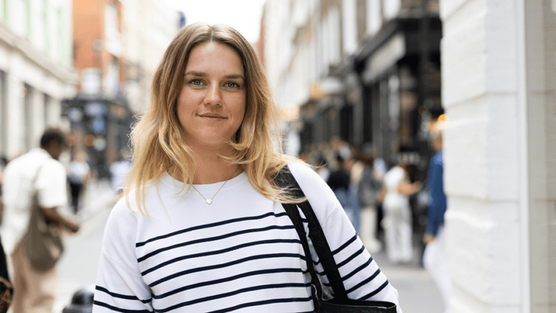 Lizzie smiles at the camera with a city backdrop