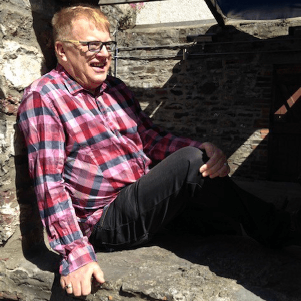 Andy smiles while sitting in a stone encavement