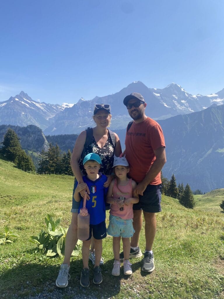 Clare stands in the mountains with her husband and two children