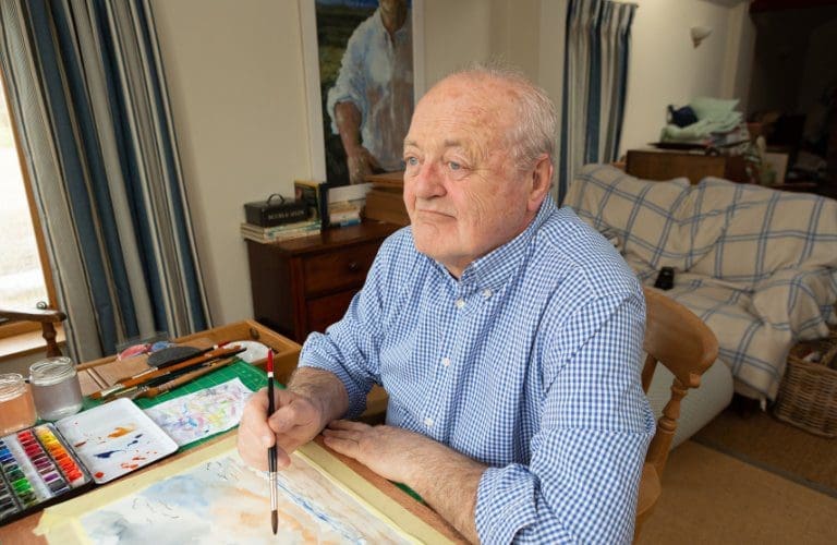 George painting at his desk.