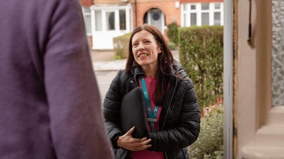 A female Admiral Nurse greets someone at their front door