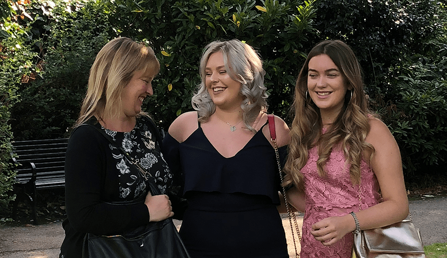 Chloe stands with her sister and Mum alongside her