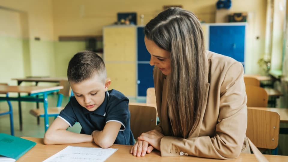 teacher sitting with a student and listening to them