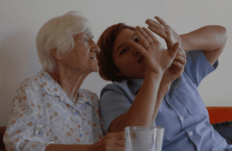 Carer sat next to elderly woman telling a story