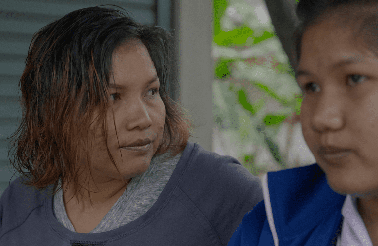 Close up headshot of two women, a mother and daughter, sat together. One is looking off in the distance, and the other is looking at her