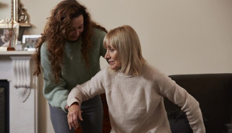 Daughter helpling her mother out of a chair