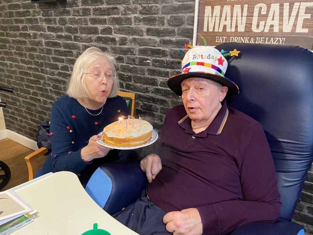 Susan holds a cake for Peter's birthday