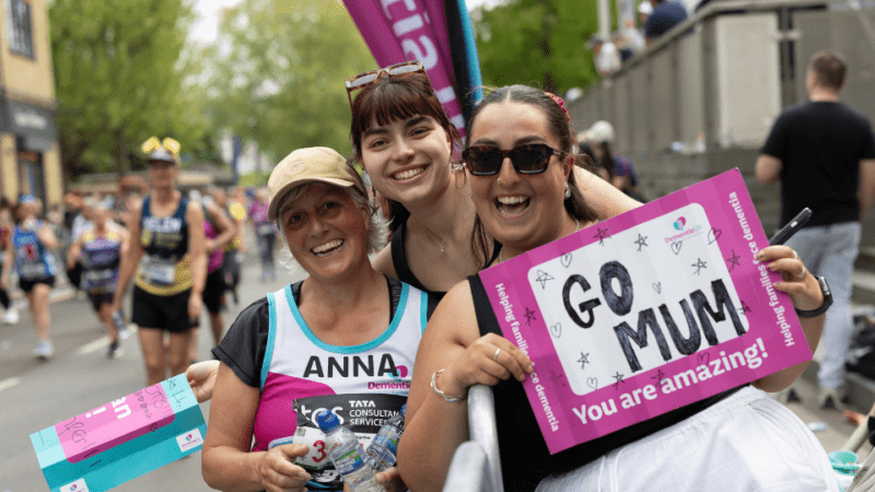 Two supporters and a fundraiser holding a sign saying 'go Mum'.