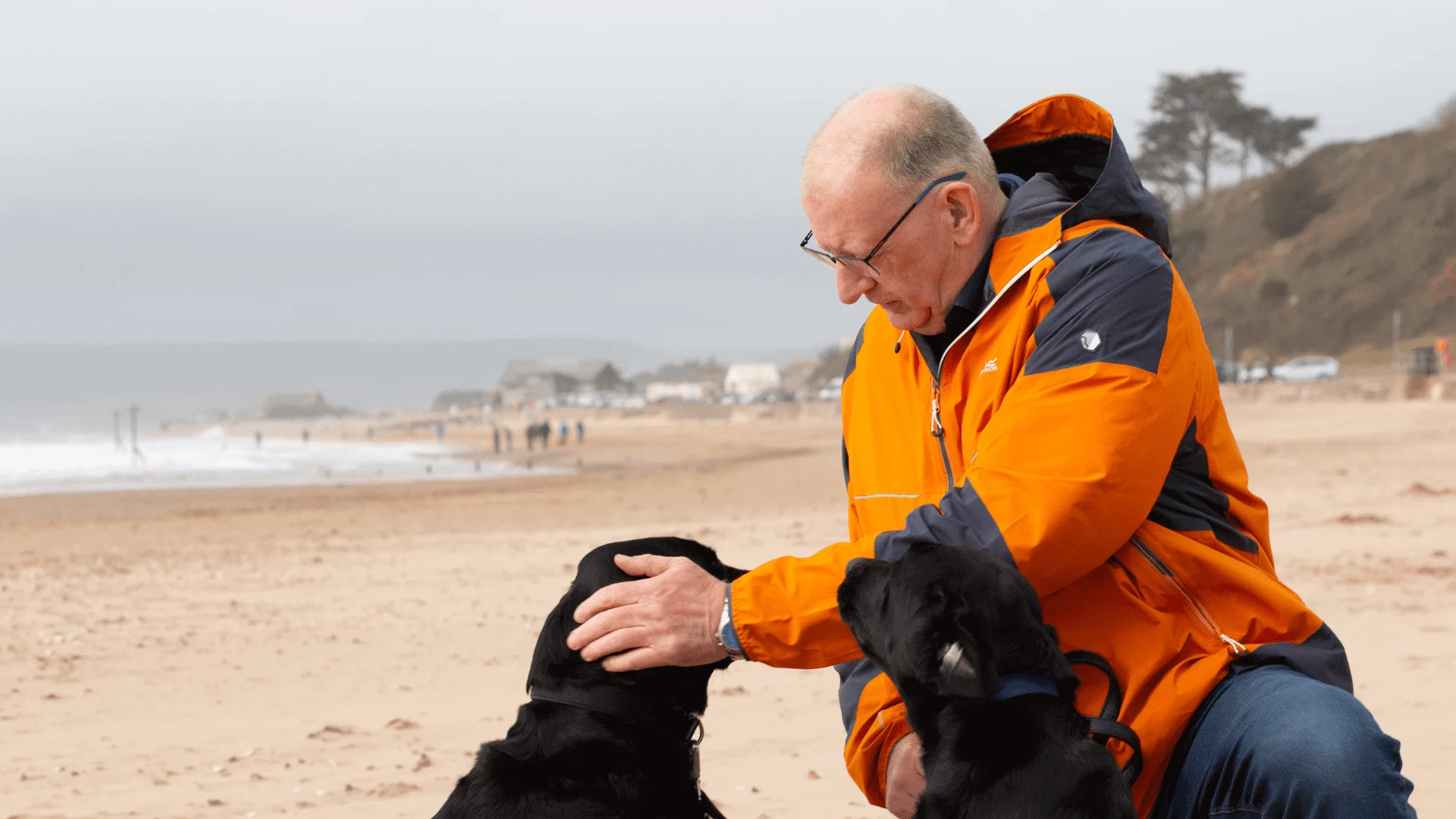 Fred with his two black labradors on a beach