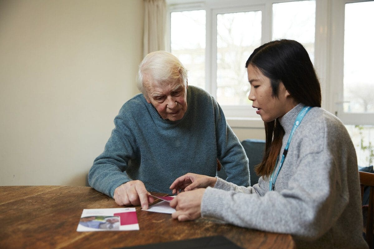 Emily, Dementia UK Admiral Nurse, talks to a man about a Dementia UK leaflet. Man is a model cast as a carer.. This photo was taken in November 2022 on location in London for the Dementia UK photo library.