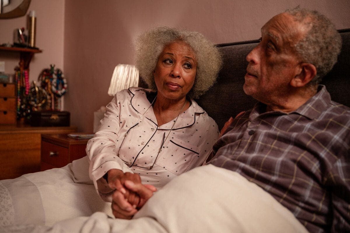 A carer at bedtime holding hands. This is a model photo shoot and the family are posed by actors on location in London.