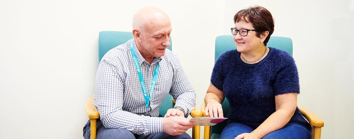 Male Admiral Nurse talking to a female carer, sitting down