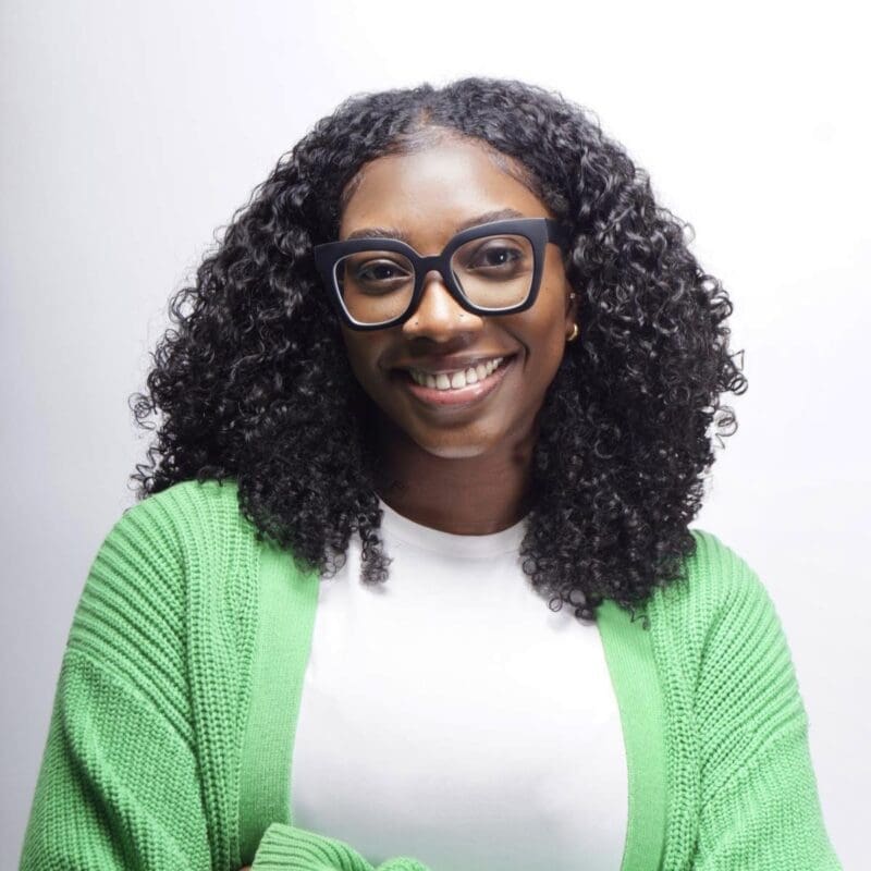 Thea Sobers smiles at camera wearing green jacket and white t-shirt.