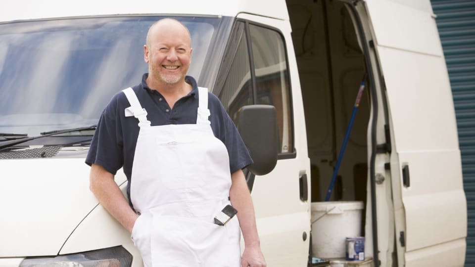 man in overalls standing in front of a van