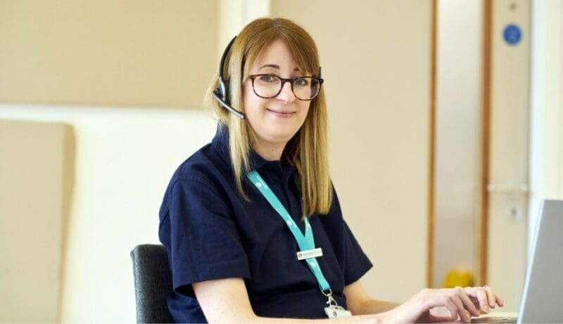 dementia specialist admiral nurse working the helpline with a headpiece to answer call and a laptop to respond to email requests