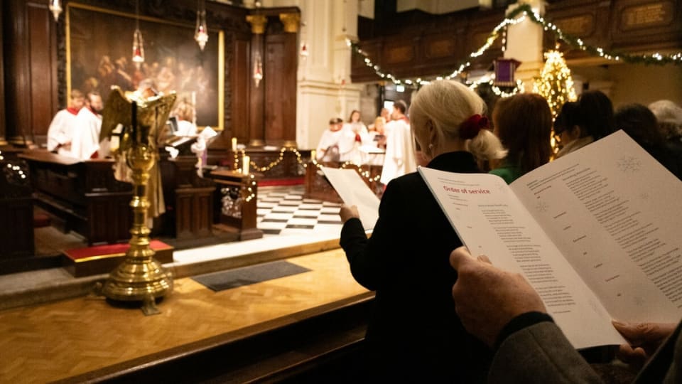 people singing along at a christmas carol concert