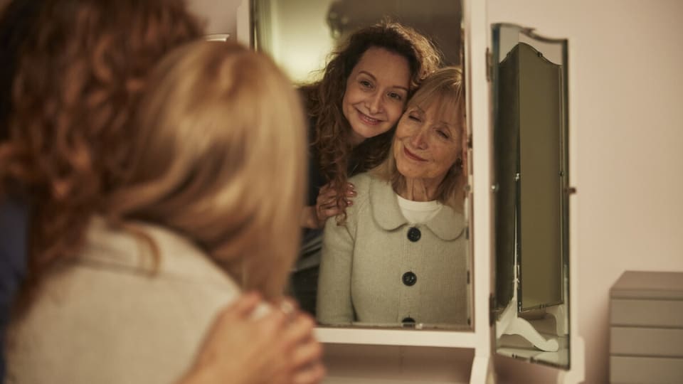 A carer helps a woman get dressed in the bedroom.