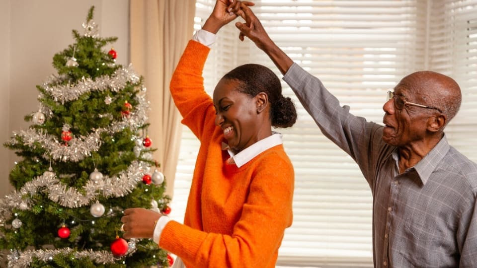 A man with dementia, supported by his daughter at home during Christmas time.