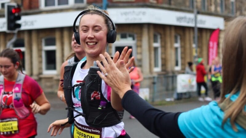 dementia uk supporter running the cardiff half marathon giving a high five to someone cheering from the side