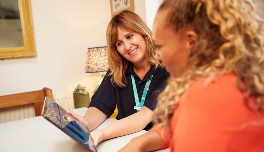 An Admiral Nurse shows a woman how to access support online using a tablet