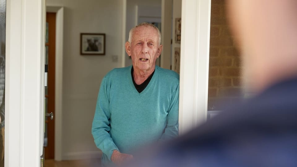 elderly man standing in the front doorway