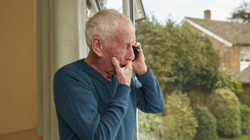 distressed elderly man making a phone call