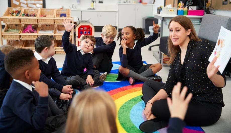 model shoot of a teacher in a circle on the floor with her class of students