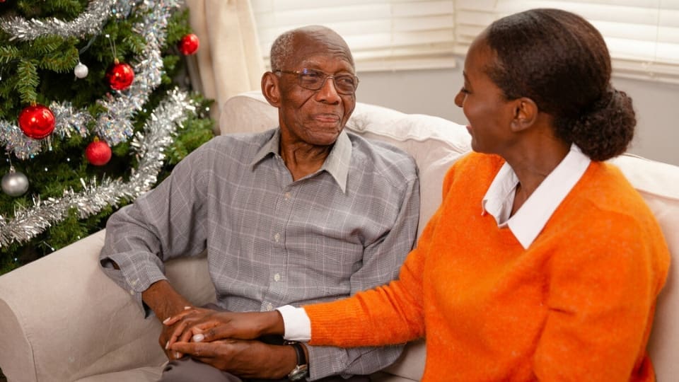 A man with dementia, supported by his daughter at home during Christmas time