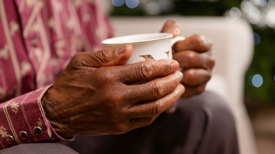 elderly man clasping a mug