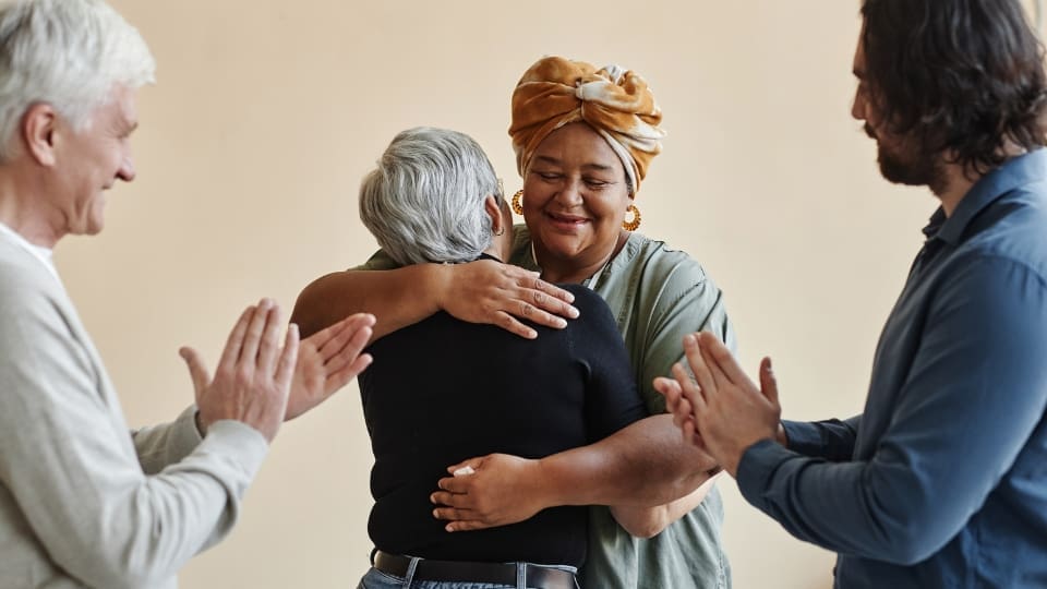 two women hug while others applaud