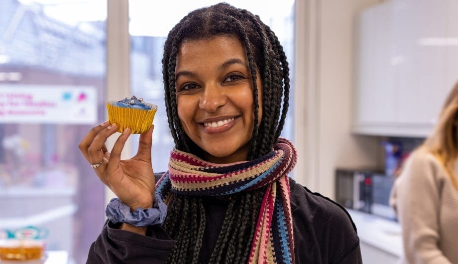 woman holding a cupcake and smiling